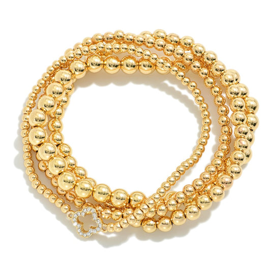 Set Of Four Metal Tone Beaded Stretch Bracelets With Rhinestone Studded Clover Accent